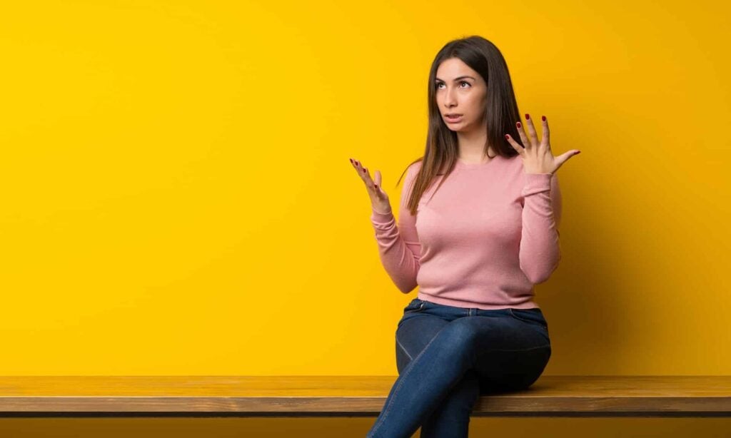 Young woman sitting on table frustrated by a bad situation