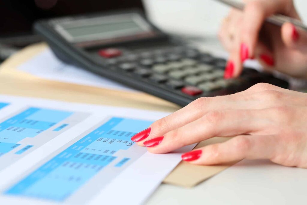 Hand of businesswoman point finger to financial table counting on calculator closeup. Internal Revenue Service inspector check statistics, investment audit, earnings, savings, loan and credit concept