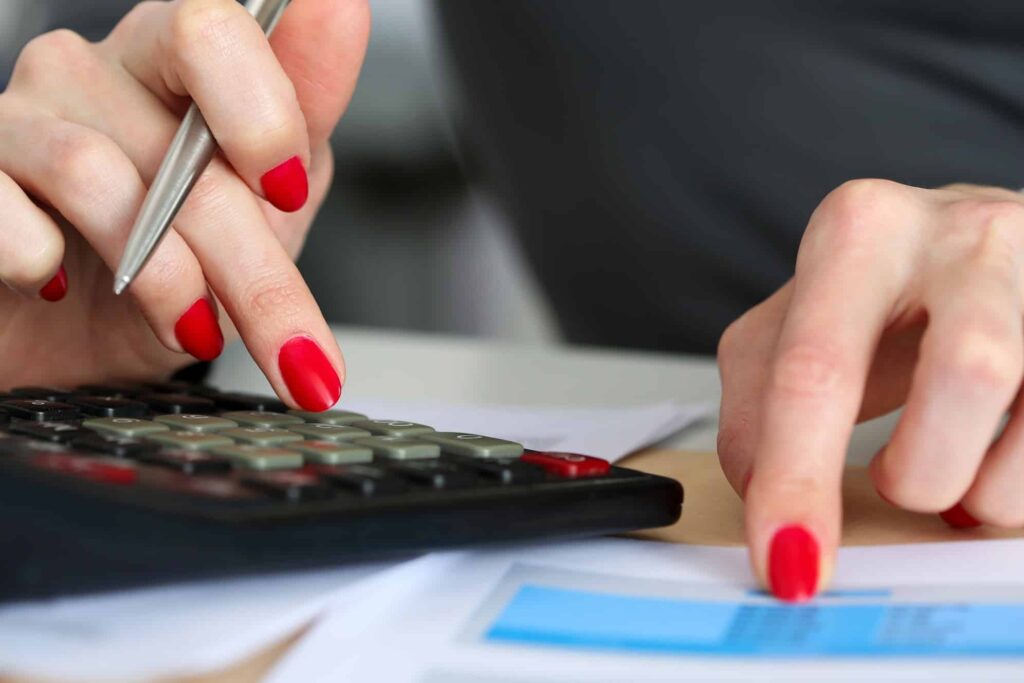 Hand of businesswoman point finger to financial table counting on calculator closeup. Internal Revenue Service inspector check statistics, investment audit, earnings, savings, loan and credit concept